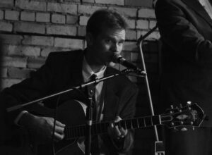 Photo of musician Sam Miltich performing on guitar.