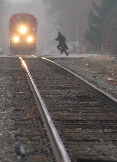 Photo by Steve Schild called Crossing, showing a train approaching with a person running to cross the tracks.