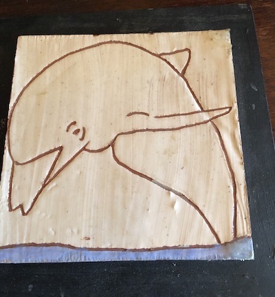 Photo of a sgraffito tile with a design of a dolphin.