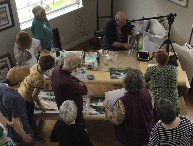Photo of workshop participants watching Jeff Nelson paint a landscape.