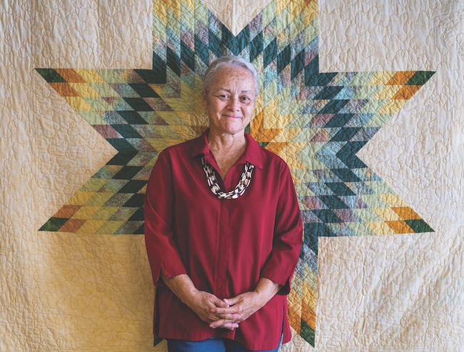 Photo of Gwen Westerman with a quilt.