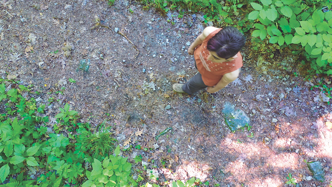 Image from above of Sharon Mansur walking on a trail; still from video by Sydney Swanson.