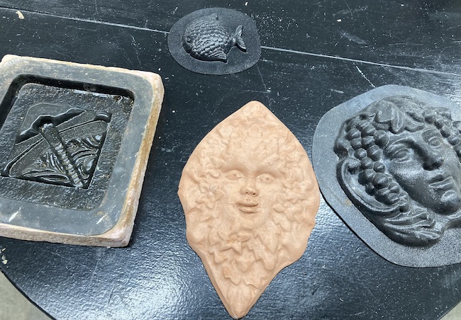 Photo of several plastic molds and a completed ceramic press mold piece.