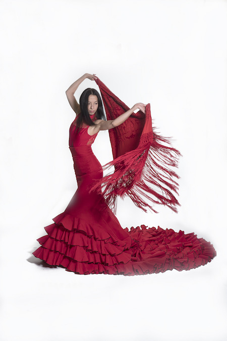 Photo of a flamenco dancer performing in a red dress with a red shawl.