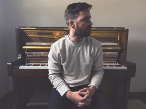 Photo of Philip Daniel with a piano.