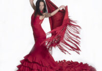 Photo of a flamenco dancer performing in a red dress with a red shawl.