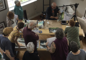 Photo of workshop participants watching Jeff Nelson paint a landscape.