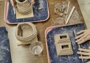 Photo of two people's hands making coiled clay pots.