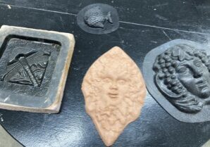 Photo of several plastic molds and a completed ceramic press mold piece.