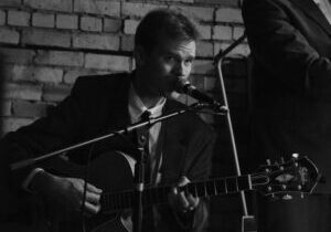 Photo of musician Sam Miltich performing on guitar.