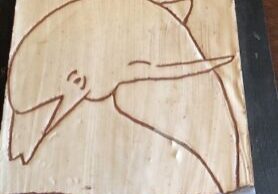 Photo of a sgraffito tile with a design of a dolphin.